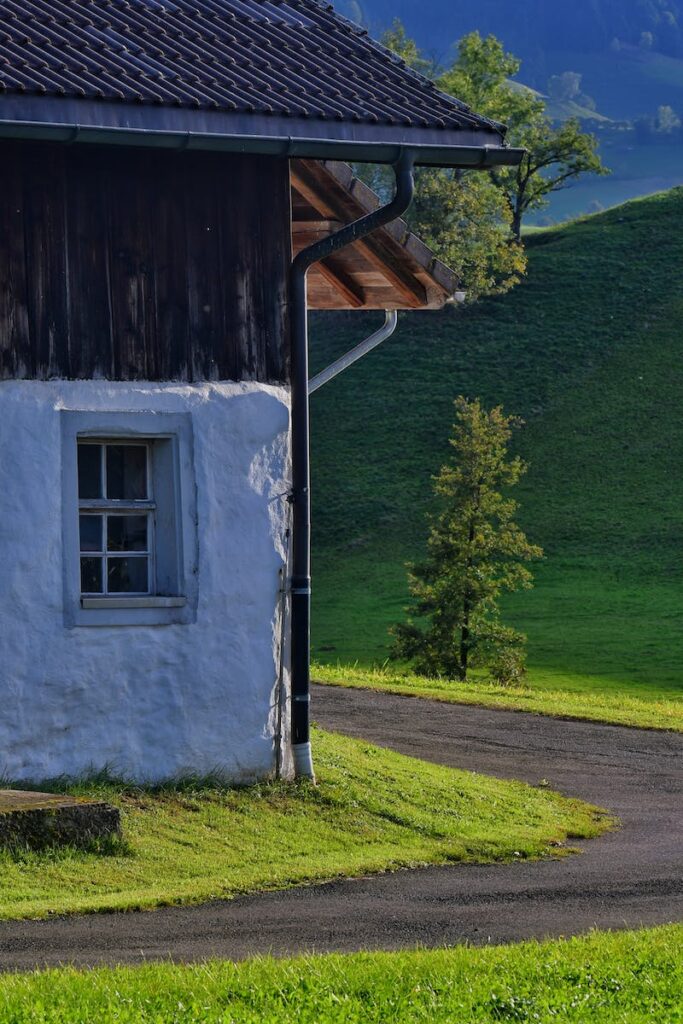 A white house with a green grassy hill in the background