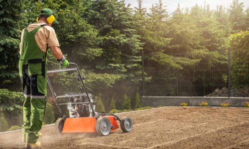 Professional Caucasian Gardener in His 40s Aerating Backyard Lawn Using Powerful Gasoline Pro Equipment. Gardening and Landscaping Industry Theme.